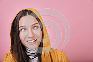 Happy lady with green eyes in yellow raincoat looks side and smiles