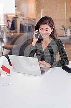 Happy lady receiving phone call while using netbook