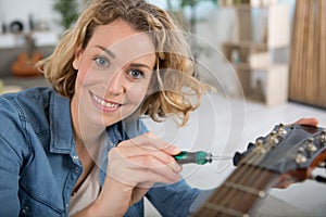 happy lady repairing acoustic guitar