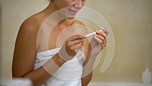 Happy lady smiling and looking at positive pregnancy test, long-expected news