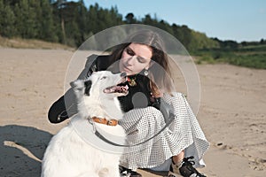 happy laika dog smiling and sitting next to its owner. young beautiful woman stroking her dog sitting on a sandy beach