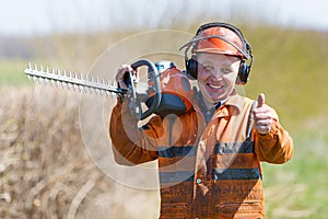 Happy Landscaper Man Worker in uniform with Hedge Trimmer Tool gersturing Ok sign