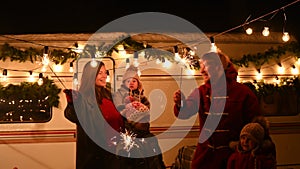 Happy large family celebrates christmas in nature and holds sparklers. Parents with three sons travels in a mobile home.