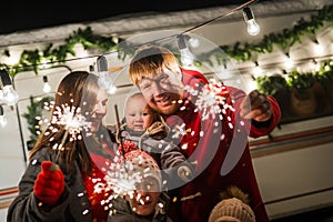 Happy large family celebrates christmas in nature and holds sparklers. Parents with three sons travels in a mobile home.