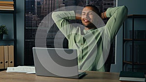 Happy latin american man finished work on laptop satisfied young businessman rest sitting at office with hands behind