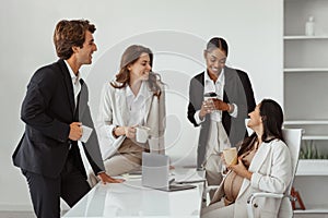 Happy latin expectant woman chatting with her multiracial business colleagues while having break in modern office