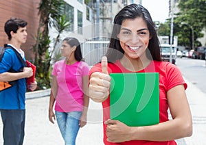 Happy latin female student in red shirt showing thumb