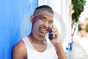 Happy latin guy at phone in front of a blue wall