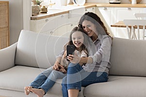 Happy Latin mom and child girl using app on smartphone