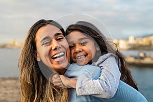 Happy Latin mother enjoying time with her child on the beach