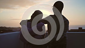 Happy Latin senior couple having romantic moment dancing on rooftop during sunset