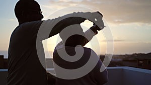 Happy Latin senior couple having romantic moment dancing on rooftop during sunset