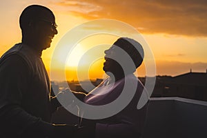 Happy Latin senior couple having romantic moment dancing on rooftop during sunset