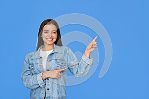 Happy Latin teen girl pointing aside standing isolated on blue background.