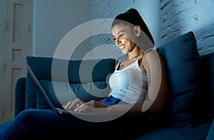 Happy latin woman working late at night on her laptop
