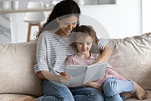 Happy Latino mom and daughter read book at home