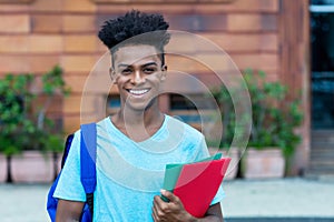 Happy laughing afro american male student with backpack and paperwork