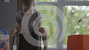 happy laughing baby boy child sitting on plastic black box driving on floor room