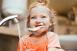 Happy laughing baby girl brushing her teeth in the bath