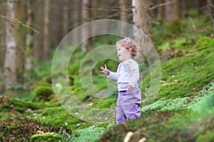 Happy laughing baby girl playing in pine forest