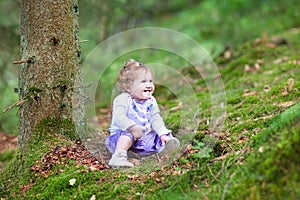 Happy laughing baby girl playing in pine wood forest