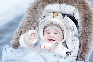 Happy laughing baby girl in warm stroller