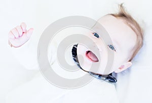 Happy laughing baby girl in a white knitted sweater