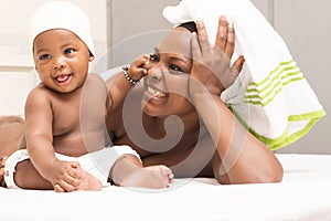 Happy laughing baby with his mother lying on the bed