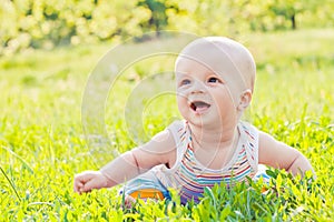 Happy laughing baby sitting on the grass
