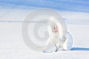 Happy laughing baby in snow on sunny winter day