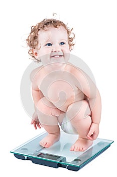 Happy laughing baby watching her weight on a scale