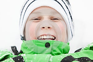 Happy laughing boy lying in winter snow