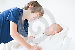 Happy laughing boy talking to newborn baby brother