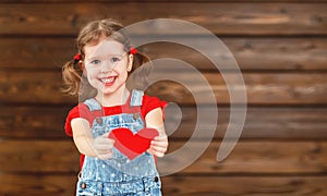 Happy laughing child girl with heart Valentine`s Day, wooden