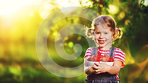 happy laughing child girl with ripe strawberry in summer on nature