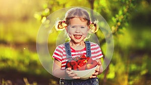 happy laughing child girl with ripe strawberry in summer on nature