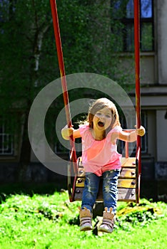 Happy laughing child girl on swing. childhood daydream .teen freedom. Playground in park. Small kid playing in summer