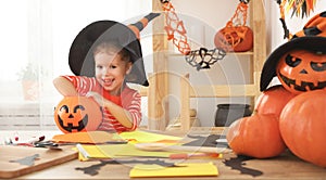 Happy laughing child girl in a witches hat eats sweets in Hallow