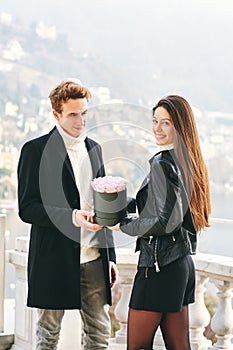 Man offering flower box of red roses to beautiful young woman