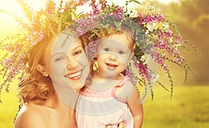 Happy laughing daughter hugging mother in wreaths of summer flow