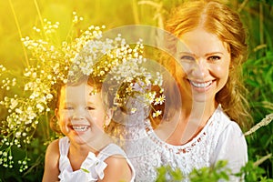 Happy laughing daughter hugging mother in wreaths of summer flow