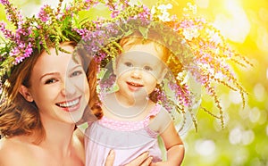 Happy laughing daughter hugging mother in wreaths of summer flow