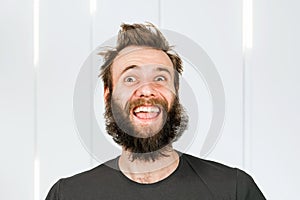 Happy laughing freak bearded shaggy man with long hair before haircut in barbershop