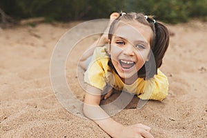 Happy laughing girl close-up lying on the sand on the beach in summer