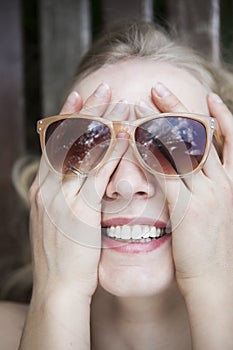 Happy, laughing girl covered her face by hands, wearing sunglasses on top