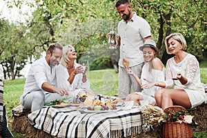 Happy laughing. Group of adult friends have a rest and conversation in the backyard of restaurant at dinner time