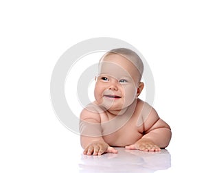 Happy laughing infant child baby girl kid in diaper is lying on her tummy holding arm outstretched, slapping on floor