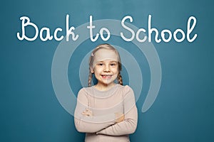 Happy laughing kid girl with inscription Back to school on blue background