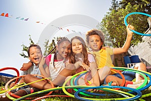 Happy laughing kids sit with hula rings in garden