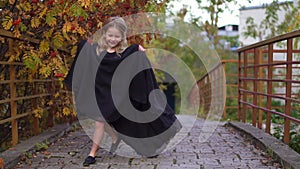 Happy laughing little girl on an autumn trail in a long black fashion dress. Halloween in a gorgeous princess dress
